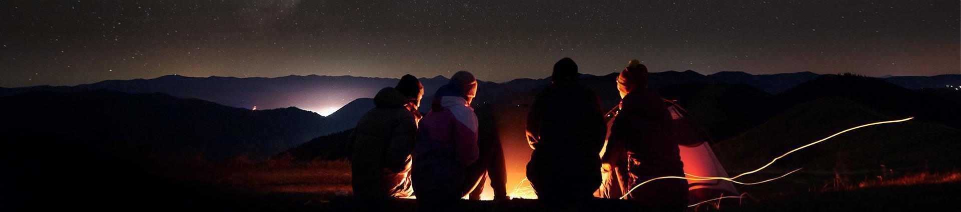grupa przyjaciół przy ognisku podczas gwieździstej nocy banner
